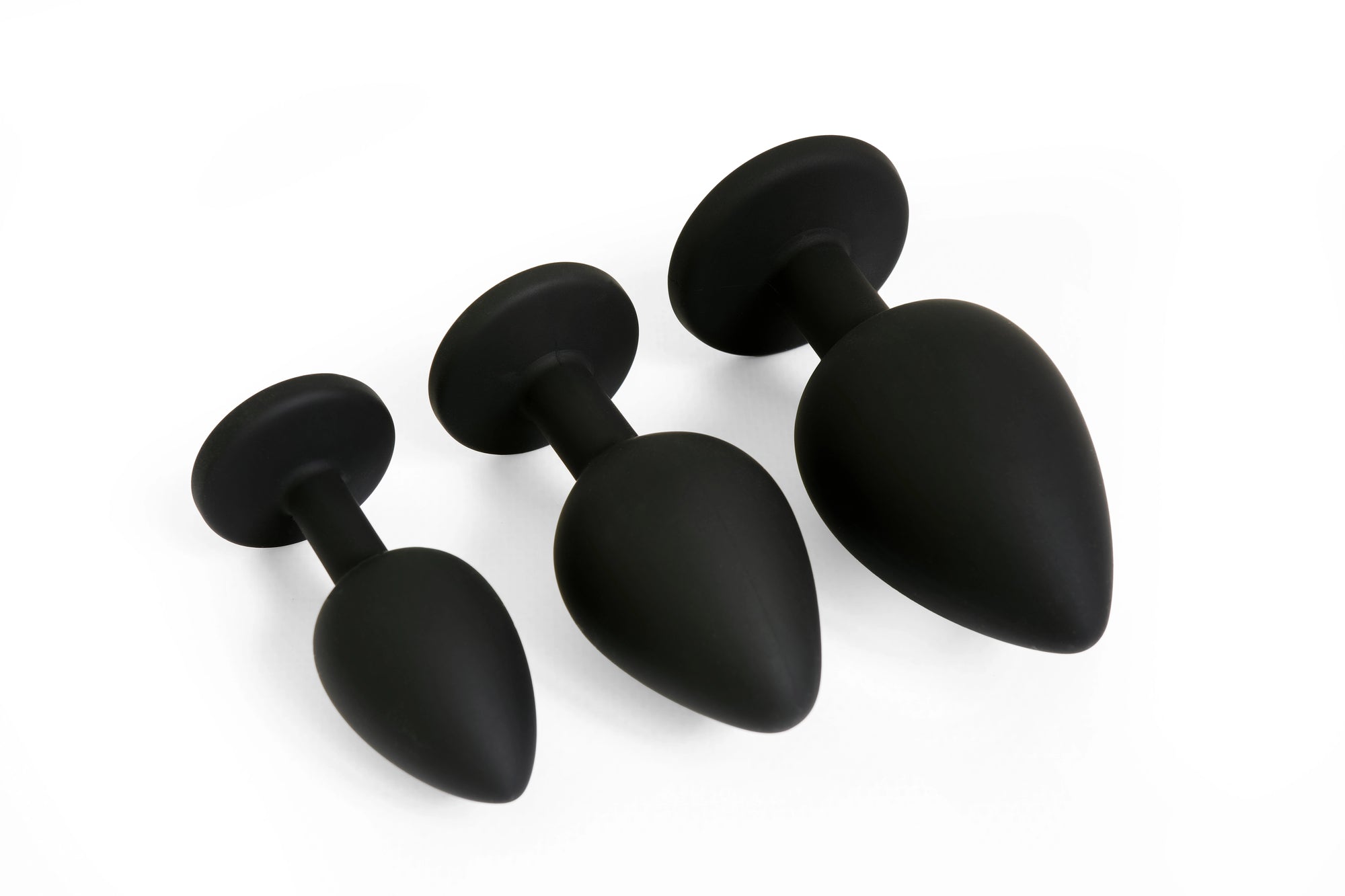Three black matte silicone butt plugs of varying sizes on a white background.