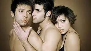 Three attractive young adults in an intimate, close-up pose against a neutral background.